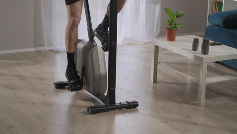 elderly-man-is-spinning-pedals-of-exercise-bike-training-at-home-spinning-pedals-in-his-living-room-at-weekend-keeping-fit-and-health-closeup-of-legs-and-feet